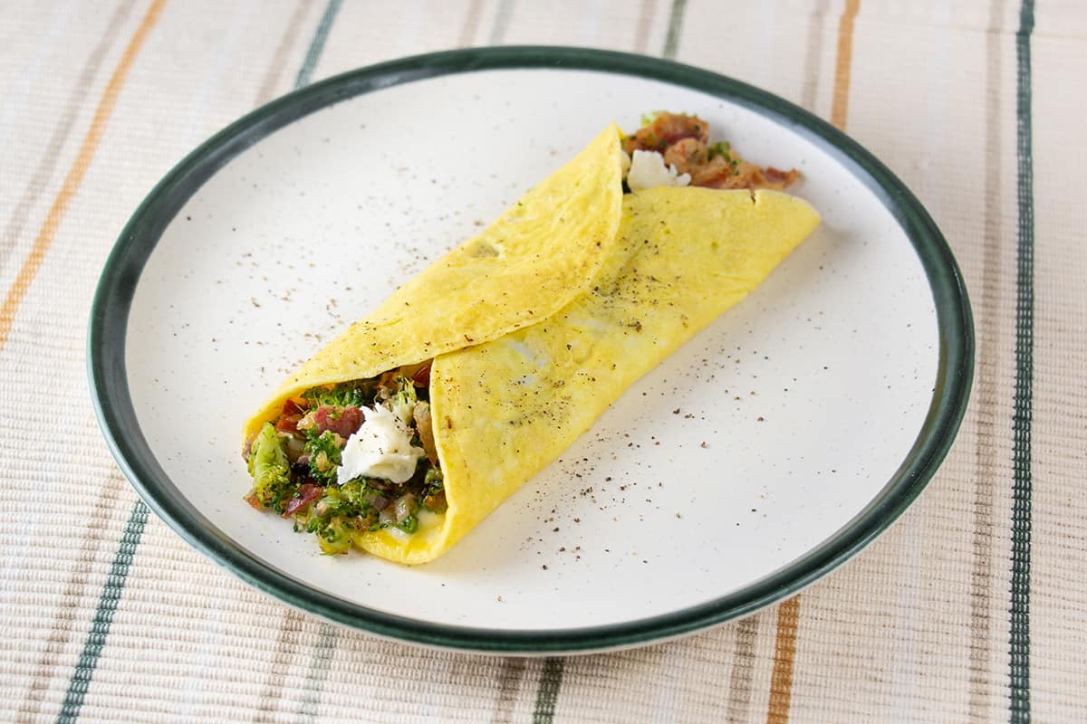 Omelette with bacon, cheese and broccoli on a white plate