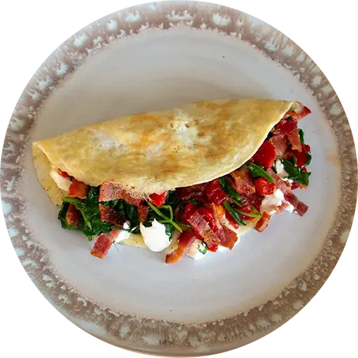 White and brown plate with an omelette filled with spinach, goat cheese, red pepper and bacon.