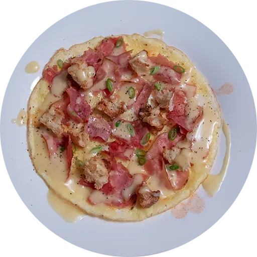 White plate with an open-faced omelette topped with toasted bread, ham and hollandaise sauce.