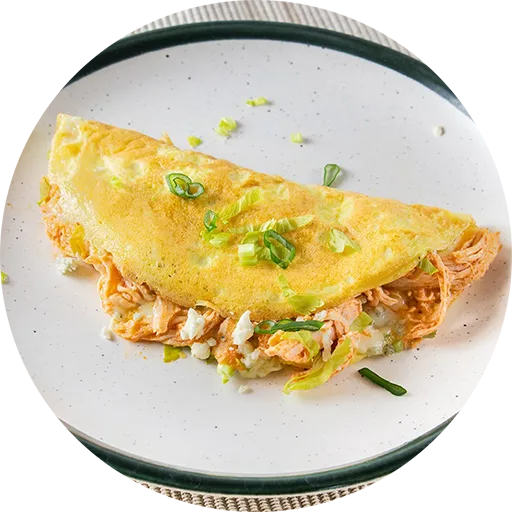 Omelette filled with chicken and celery in an orange sauce, all on a white plate with a green edge.