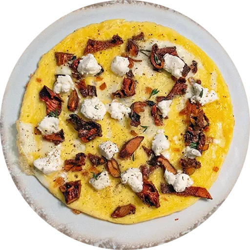 White and brown plate with an open-faced omelette on it. It is topped with chanterelle mushrooms, goat cheese and fresh thyme.