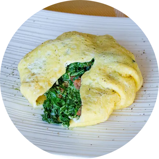 White square plate with a round omelette stuffed with creamy spinach.