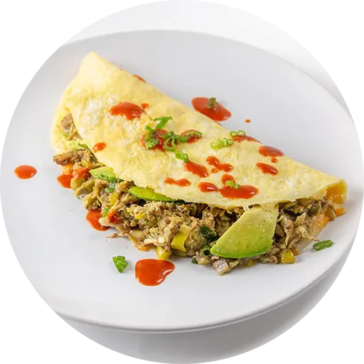 Omelette on a white plate filled with chicken and avocado.
