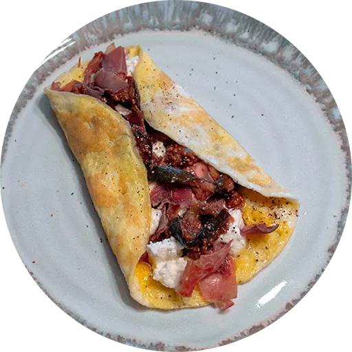 White and grey plate with an omelette filled with prosciutto, fig and goat cheese.