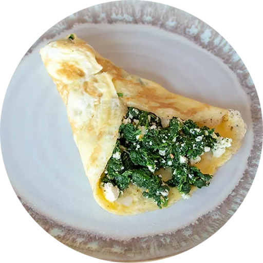 White and brown plate with an omelette stuffed with spinach and feta cheese.