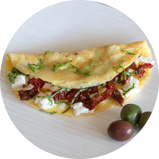 White plate with an omelette filled with goat cheese, tomatoes and basil. Three olives sit beside the omelette.