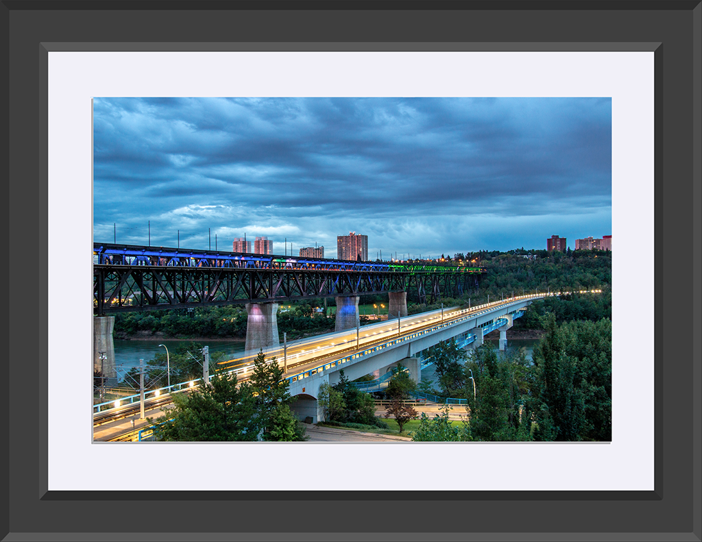 Two bridges in the early morning, dark blue cloudy sky, coloured lights on the bridge.