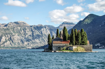 Buildings on a small island in a lake surrounded by mountains.
